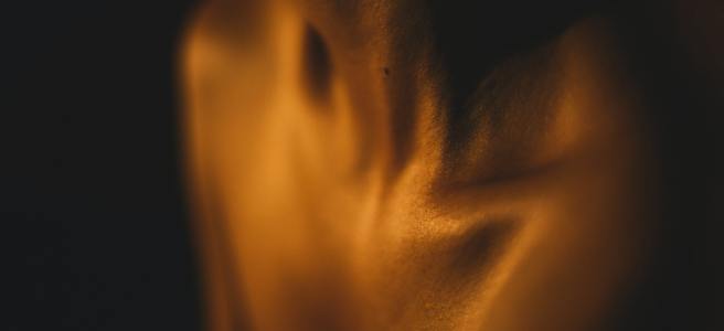 an erotic close-up of someone's bare throat under gold lights